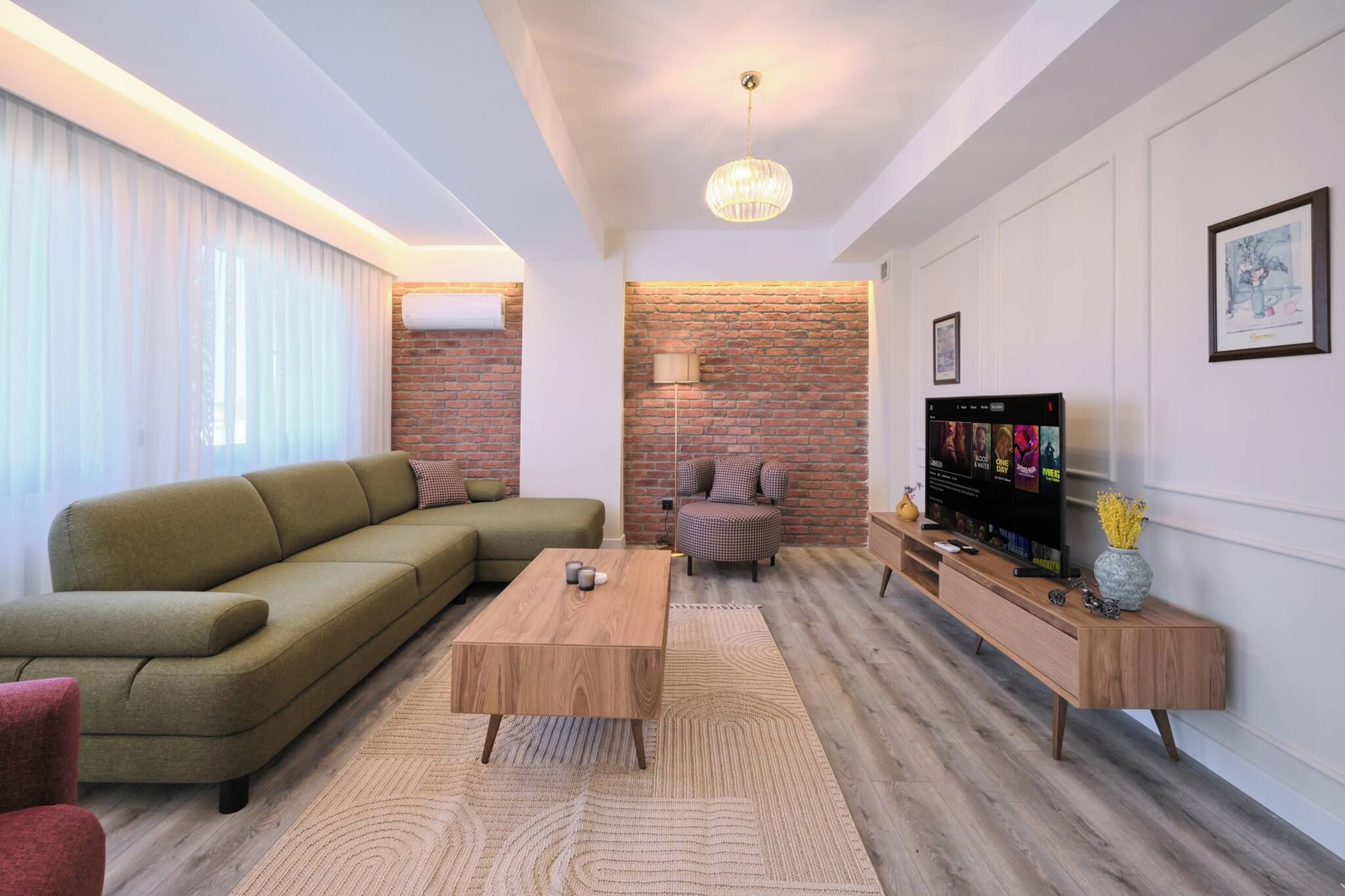 Een moderne woonkamer met een bank, salontafel en een televisie op een houten standaard.