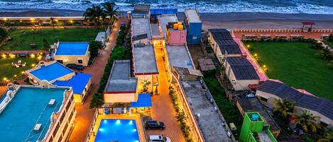 A coastal hotel with a swimming pool, multiple buildings, and a beach view.