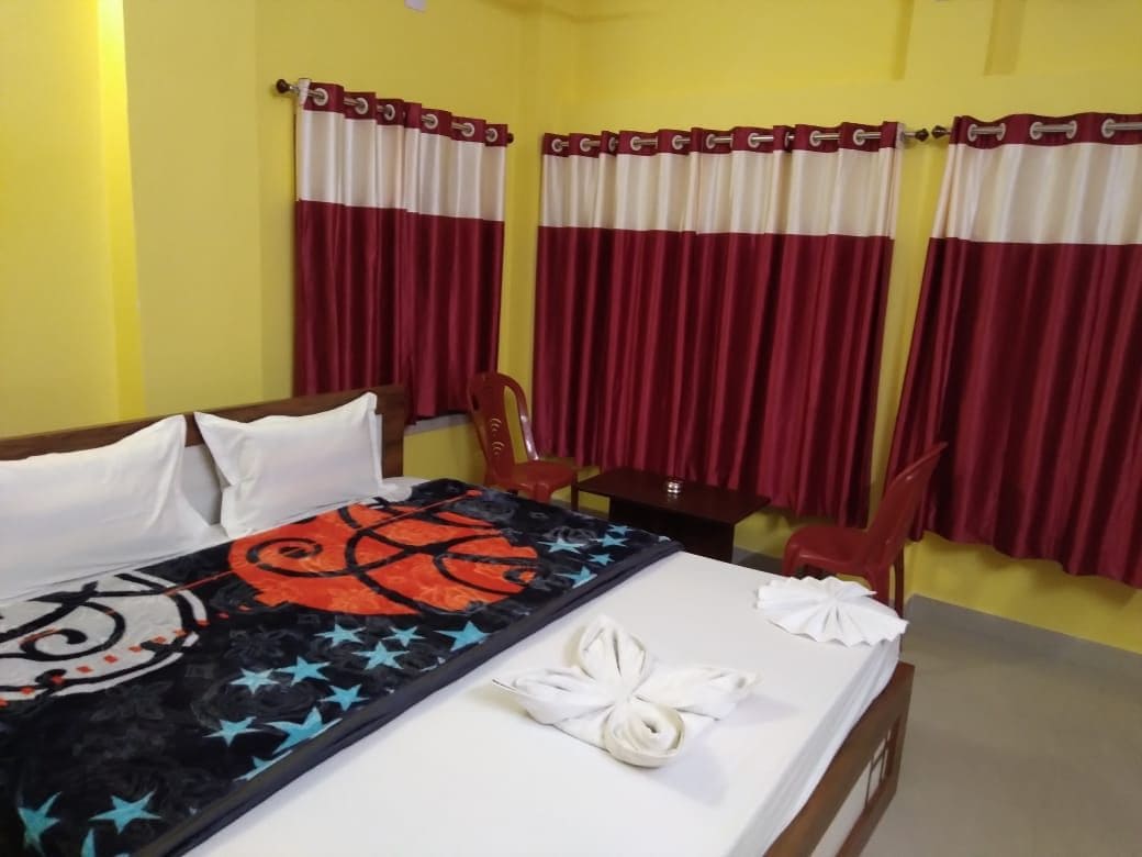 Habitación de hotel con una cama, un escritorio y una silla. Hay cortinas en las ventanas.