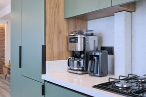 Et moderne køkken med indbygget kaffemaskine, en brødrister og en gasblus.