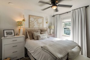 A bedroom with a bed, bedside tables, a ceiling fan, and a window with curtains. - < 1 Mi to Fort Jackson: Condo w/ Private Patio (Columbia)