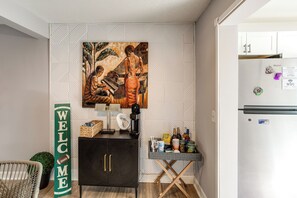 A kitchen area with a refrigerator, a coffee machine, a small table with condiments, and a welcome sign. - < 1 Mi to Fort Jackson: Condo w/ Private Patio (Columbia)