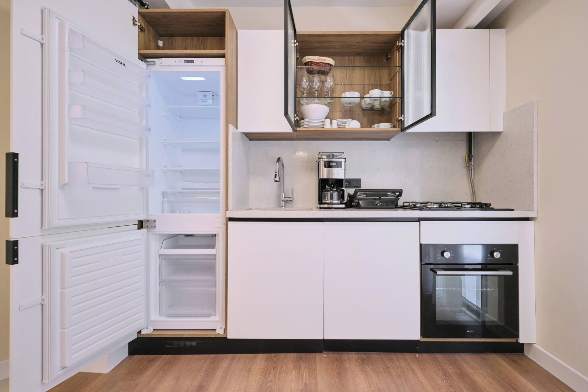 A compact kitchen with a built-in refrigerator, a coffee maker, a stove, and an oven.