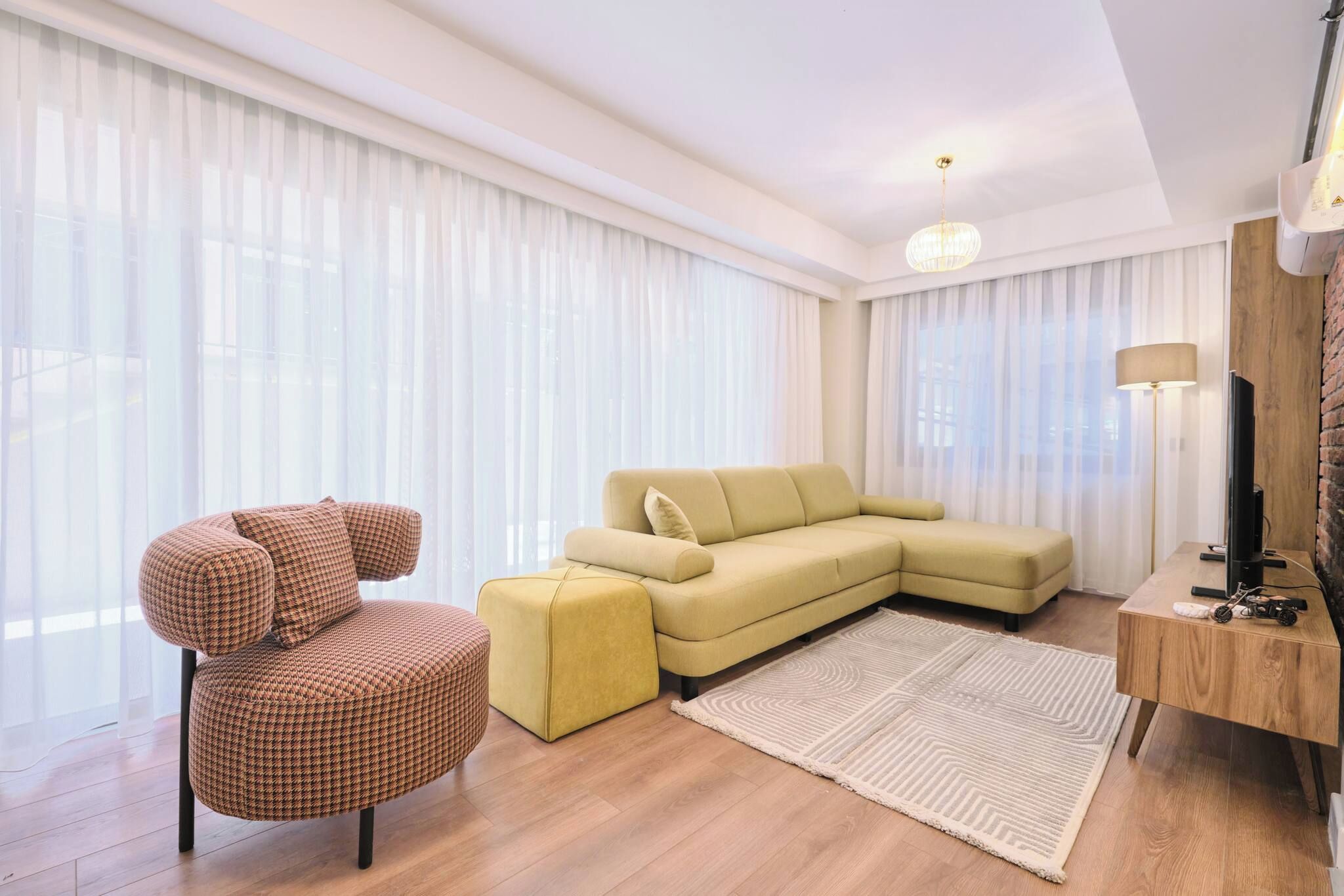 A modern living room with a sofa, a chair, a rug, and a TV stand.