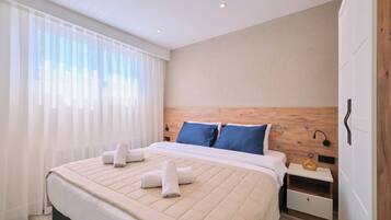 A hotel room with a large bed, two pillows, a nightstand, and a wooden headboard.