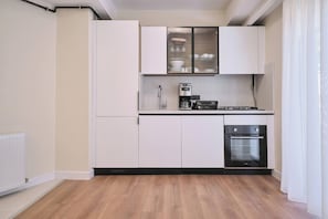 Eine kompakte Küche mit weißen Schränken, einem eingebauten Backofen und einer Kaffeemaschine.