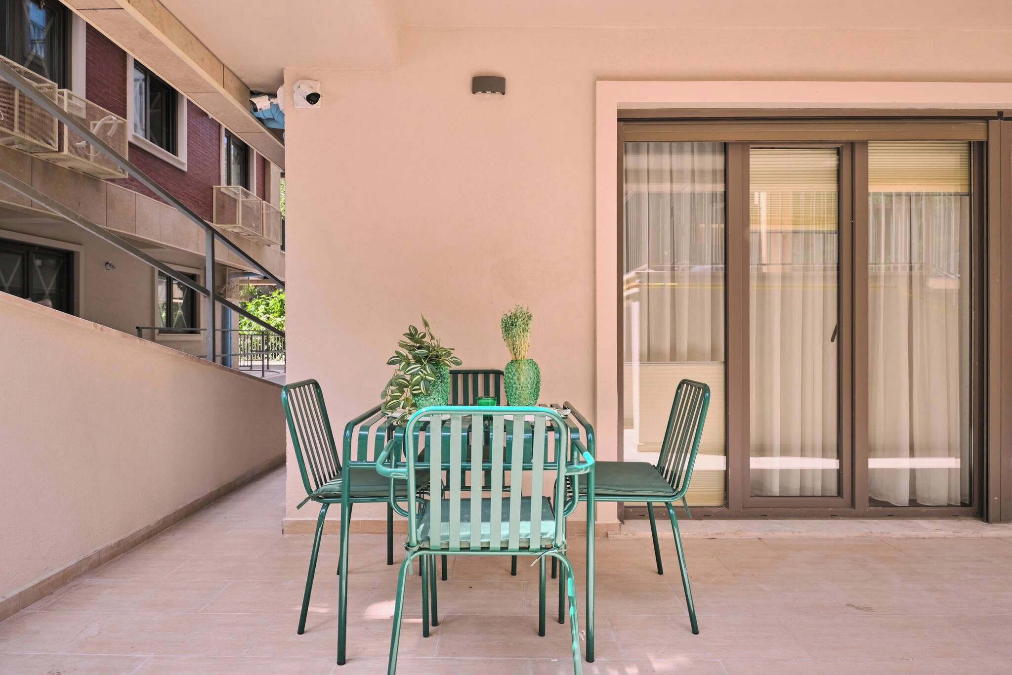 Un balcon avec une table et des chaises, un pot de fleurs et une porte-fenêtre coulissante.