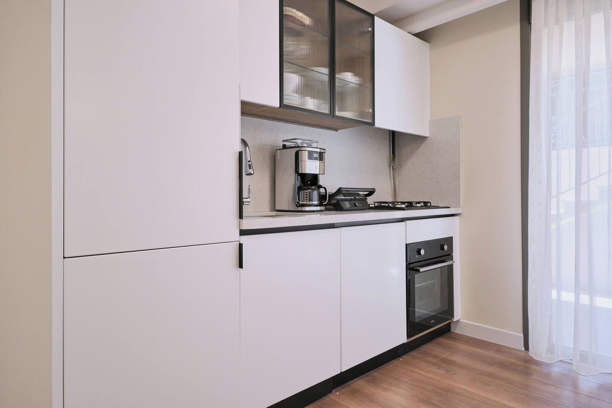 A kitchen with white cabinets, a coffee maker, and a stove.
