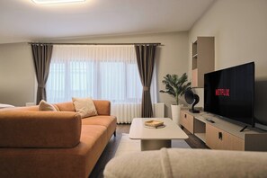 Ett modernt vardagsrum med en soffa, ett soffbord, en tv och en växt.