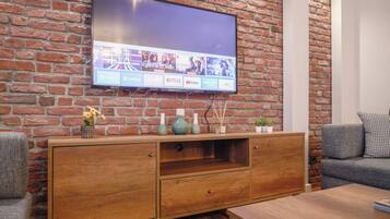 A flat-screen TV mounted on a brick wall with a wooden entertainment unit below.
