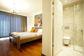 Een slaapkamer met een bed, een badkamer met een glazen douchecabine en een schilderij aan de muur.