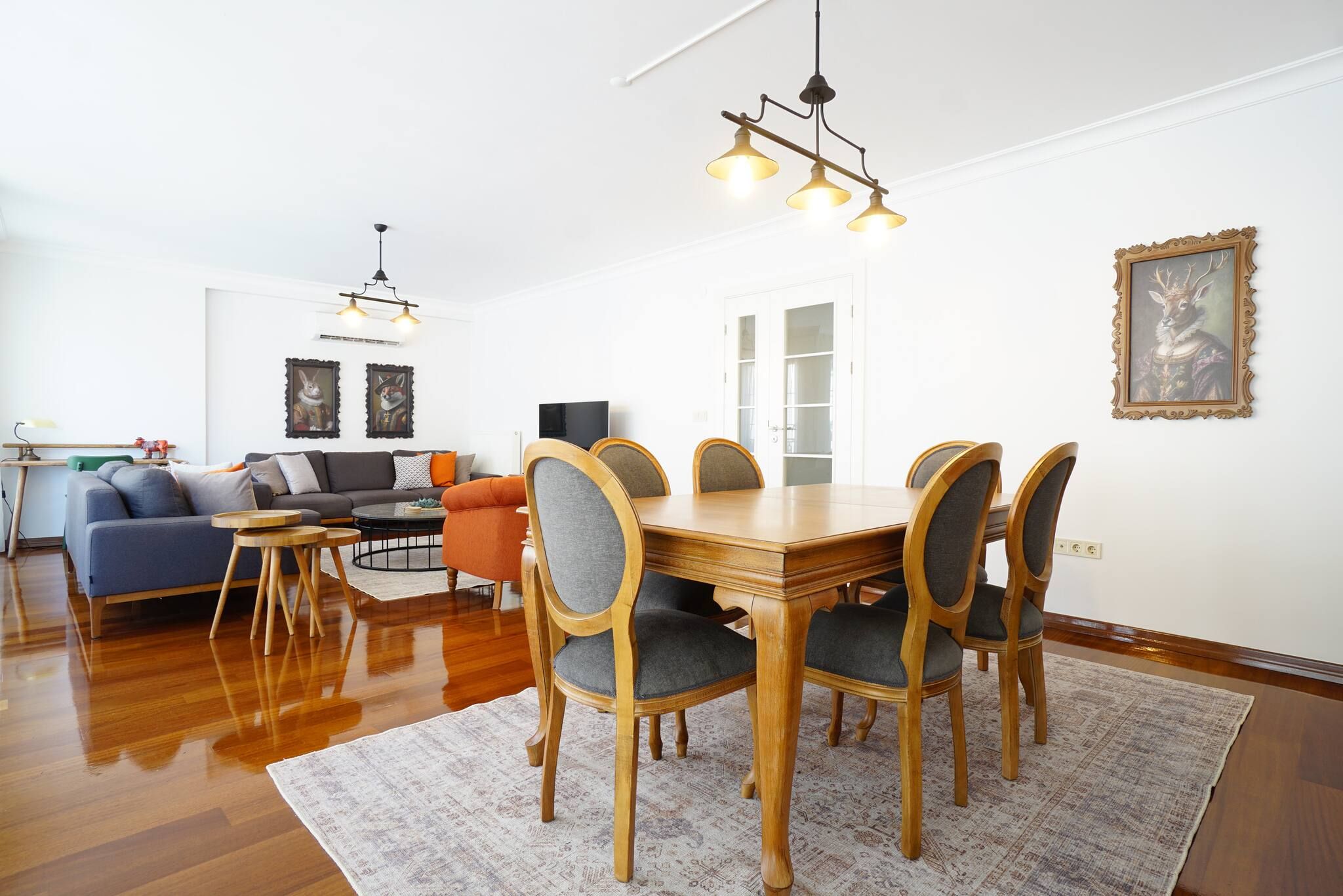 A dining area with a wooden table and chairs, a sofa, and a television in the background.