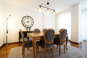 A dining room with a wooden table and chairs, a large wall clock, and a floor lamp. - Elite, Tastefully Furnished, 3BR (Kadıköy)