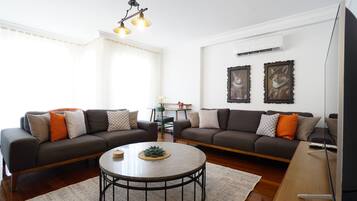 A living room with two sofas, a coffee table, and a wall-mounted TV.