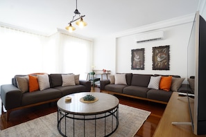 A living room with two sofas, a coffee table, and a wall-mounted TV. - Elite, Tastefully Furnished, 3BR (Kadıköy)