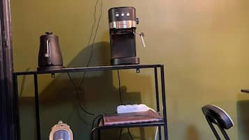 Una stanza con una macchina del caffè, uno specchio e uno scaffale con un libro e un oggetto decorativo.