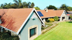 Een woongebouw met een schuin dak, zonnepanelen en een verzorgd gazon.
