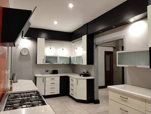 A modern kitchen with white cabinets, a gas stove, and a microwave.