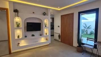A modern living room with a flat-screen TV, recessed lighting, and a view of the outdoors.