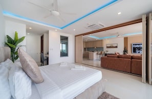 A modern bedroom with a bed, bedside table, and a view into the living area. - Apartment with Sea View and Hot Tub on Balcony (Rawai)
