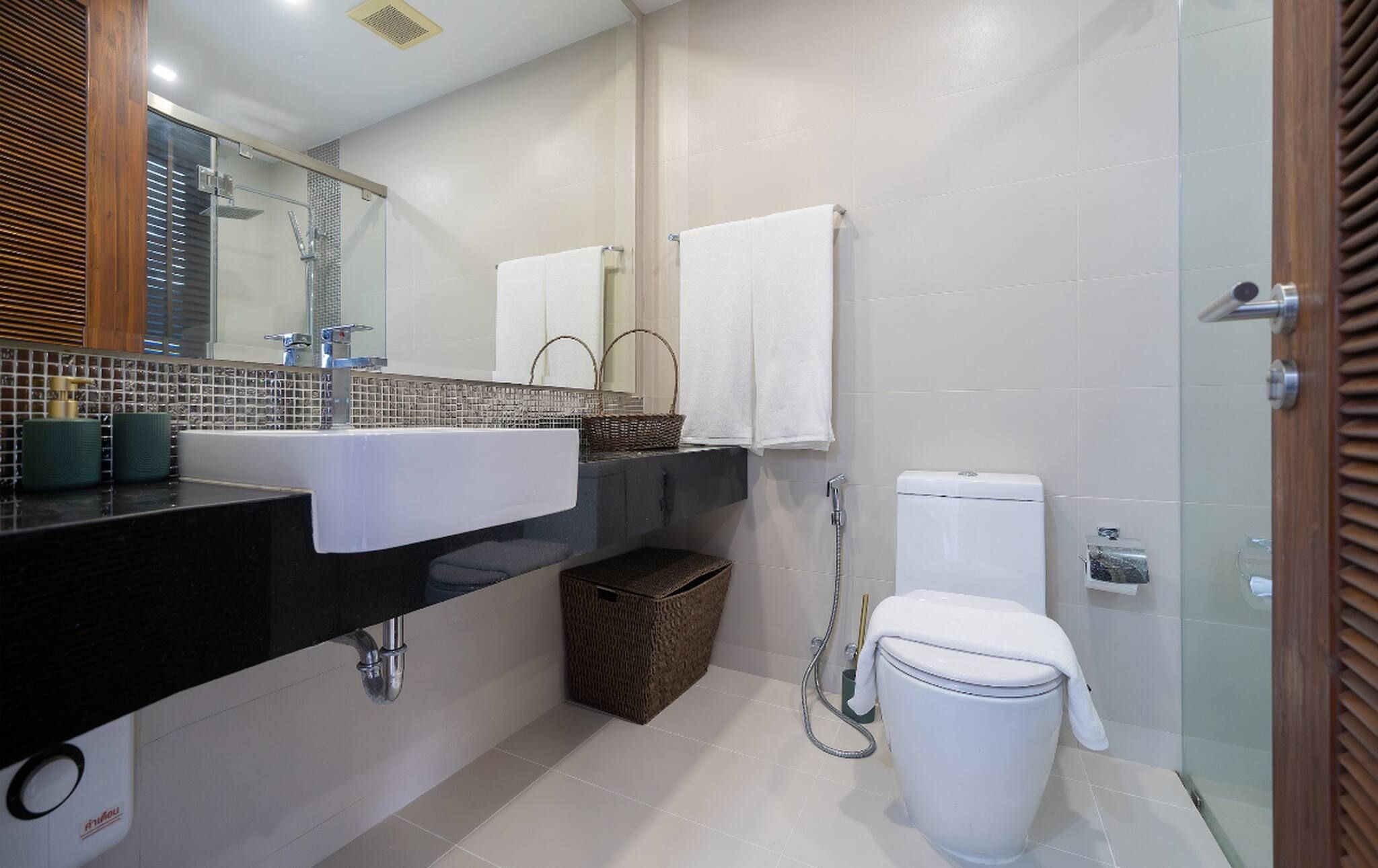 A modern bathroom with a black sink, a glass shower enclosure, and a white toilet.