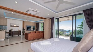 Een moderne hotelkamer met een groot bed, een zithoek, een eethoek en een balkon met uitzicht.