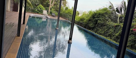 Una piscina infinita con terraza de madera y vista al océano.