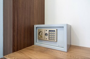 Un coffre-fort doté d’un clavier et d’une serrure à combinaison, posé sur une surface en bois, adossé à un mur.