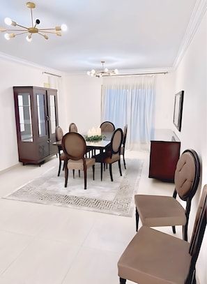 Uma sala de jantar com mesa redonda, cadeiras, armário e luminária no teto.