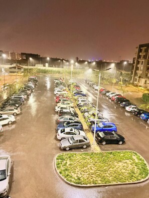 Estacionamento com várias fileiras de carros estacionados e um espaço central com paisagismo.