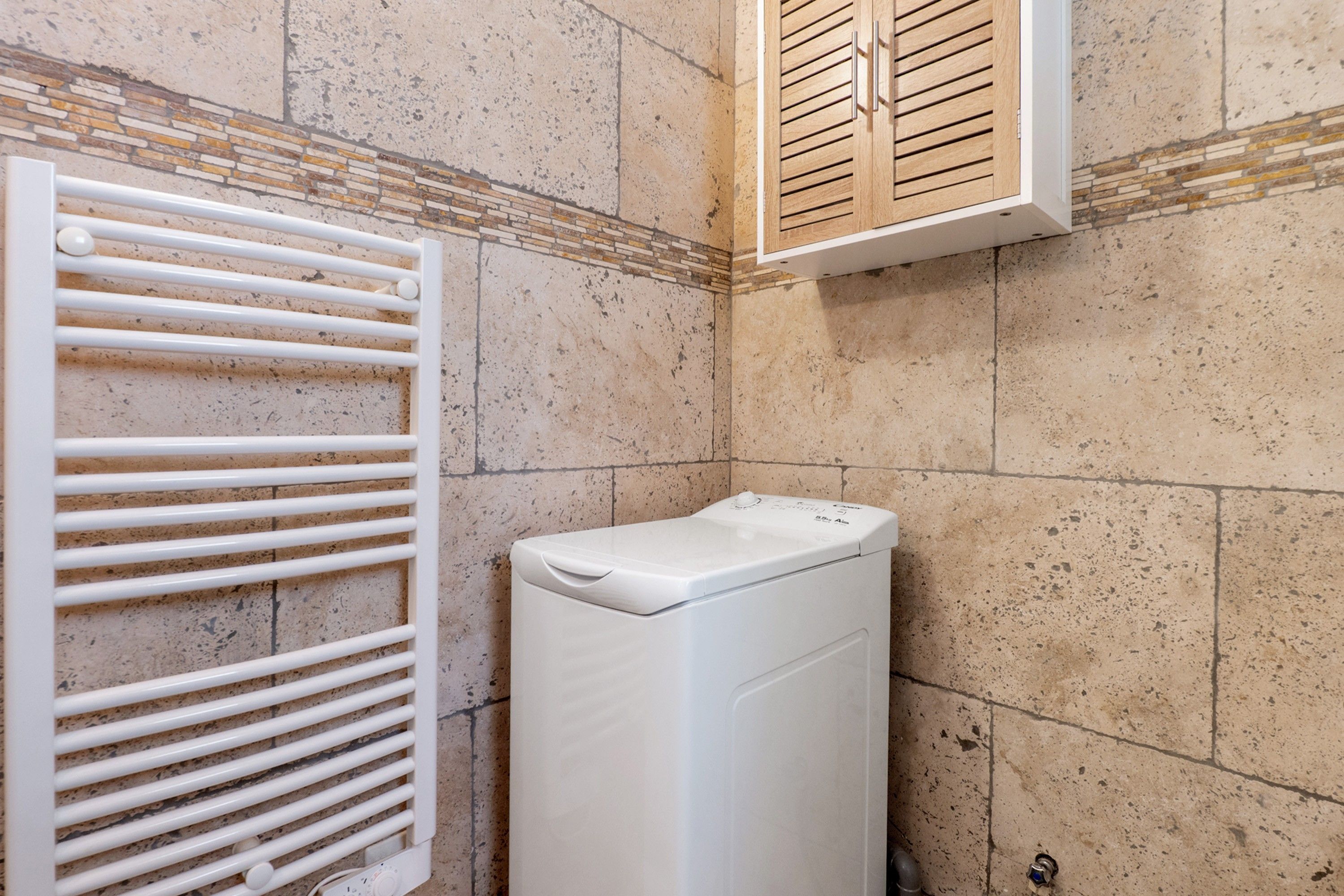A laundry area with a white dryer and a vented drying rack.