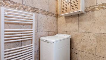 A laundry area with a white dryer and a vented drying rack.