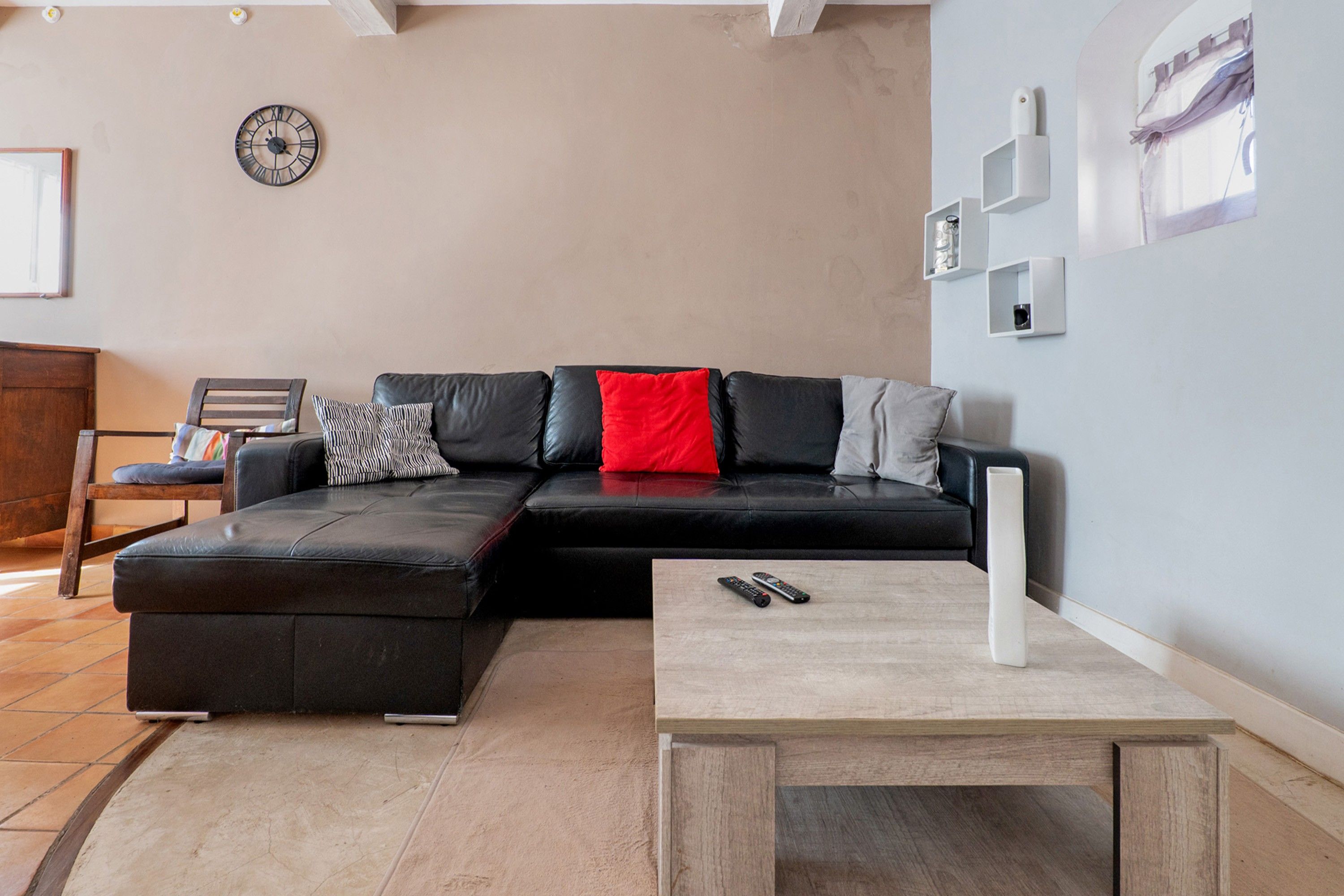 Una sala de estar moderna con un sofá modular, una mesa de centro y un reloj en la pared.