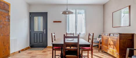 Un coin repas avec une table et des chaises en bois, une porte noire et une fenêtre avec des rideaux.
