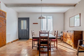 Un coin repas avec une table et des chaises en bois, une porte noire et une fenêtre avec des rideaux.