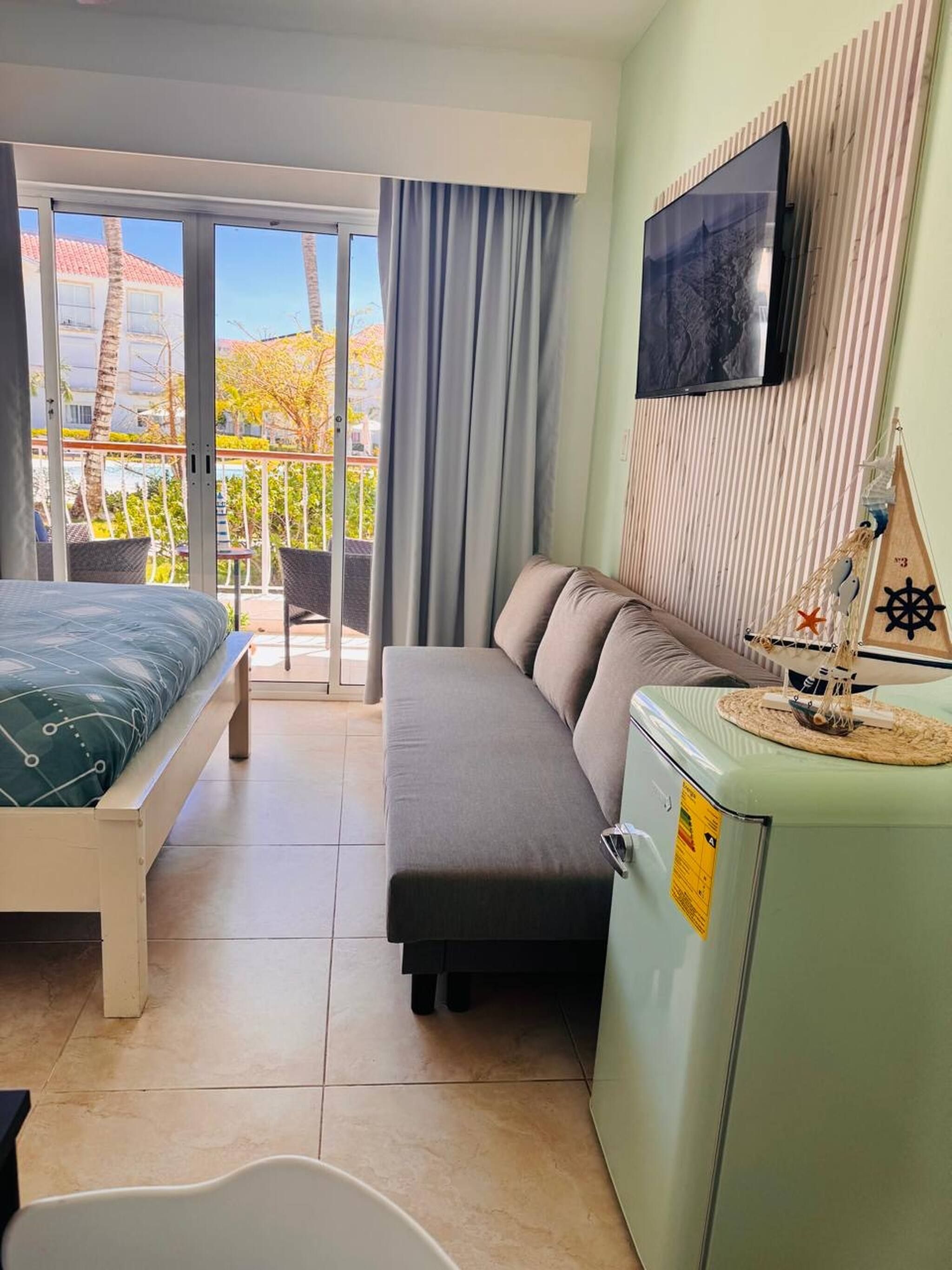 Ein Hotelzimmer mit Bett, Sofa, Fernseher und einer kleinen Küchenzeile.