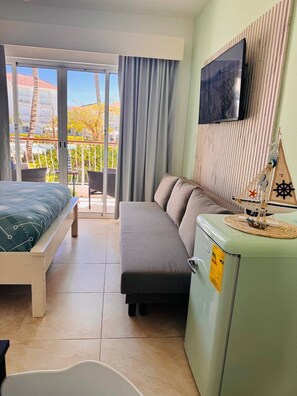 Ein Hotelzimmer mit Bett, Sofa, Fernseher und einer kleinen Küchenzeile.