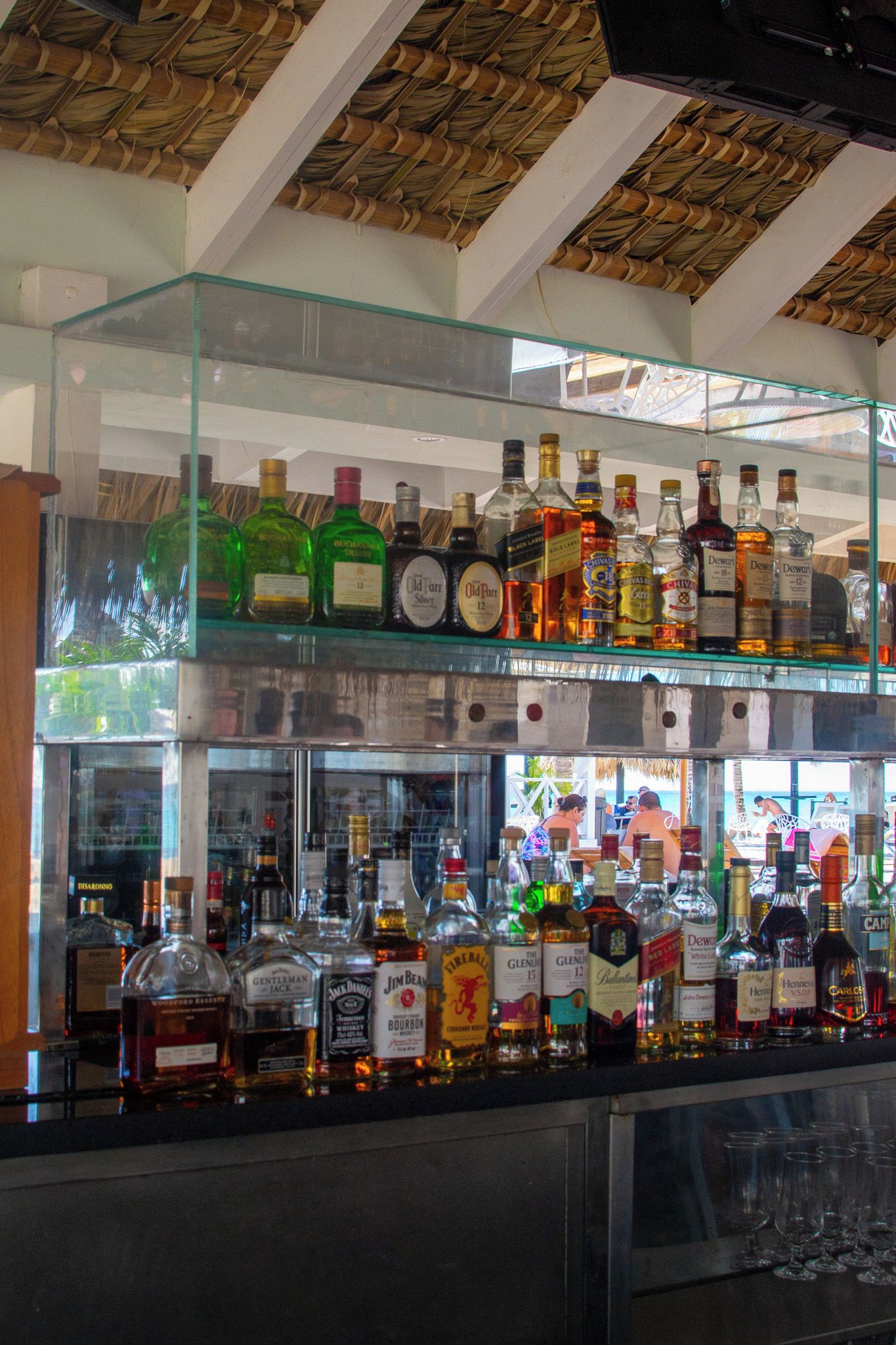 Eine Bar mit mehreren Regalen voller Spirituosenflaschen und Gläsern darunter.