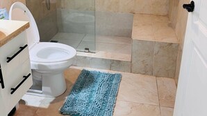 Kylpyhuone, jossa on lasiseinällä varustettu suihku, wc ja pesuallas.