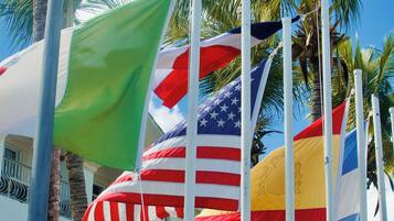 A building with multiple flags, including the American flag, and palm trees in the background.