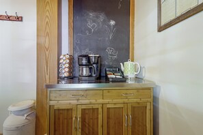 A kitchenette with a coffee maker, a kettle, and a tea pot on the counter.