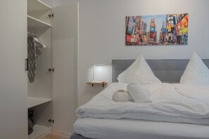 Une chambre d’hôtel avec un lit, une table de chevet, un tableau représentant un paysage urbain et une armoire.
