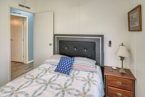 Une chambre à coucher avec un lit, une table de chevet, une lampe et une porte.