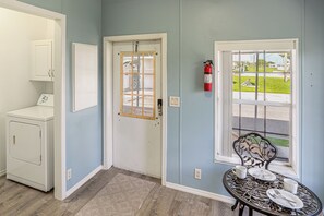 A room with a door, a window, a fire extinguisher, a cabinet, and a table with plates and a cup. - Waterfront Escape w/ Private Dock! Okeechobee Lake (Okeechobee)