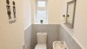 Ein kleines, modernes Badezimmer mit Toilette, Waschbecken und Fenster.