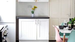 Eine Küche mit weißen Schränken, einer schwarzen Arbeitsplatte und einem Essbereich mit Tisch und Stühlen.