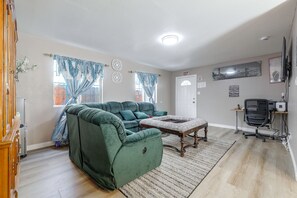 A living room with a green sofa, a coffee table, a TV, and a computer desk.
