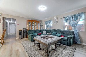 A living room with a sectional sofa, a coffee table, a wooden cabinet, and a refrigerator.