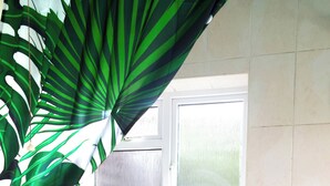 Ein Badezimmer mit einer weißen Badewanne, einem Fenster und einer Pflanze.