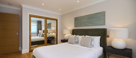 A bedroom with a bed, bedside tables, a mirror, and a ceiling light.